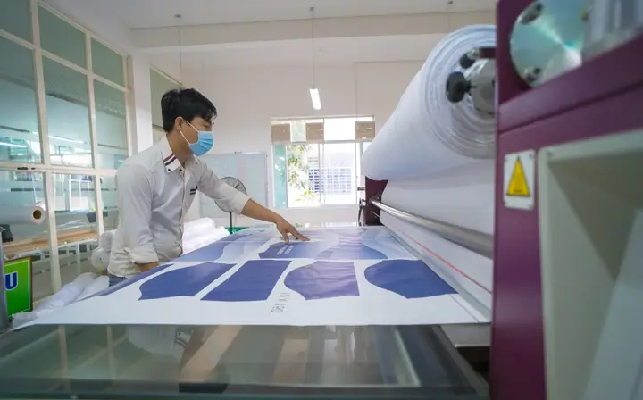 young asian male worker technician wearing medical mask make object on sublimation heat press