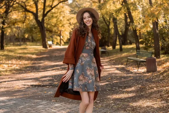 Smiling woman with curly hair walking in park wearing printed dress