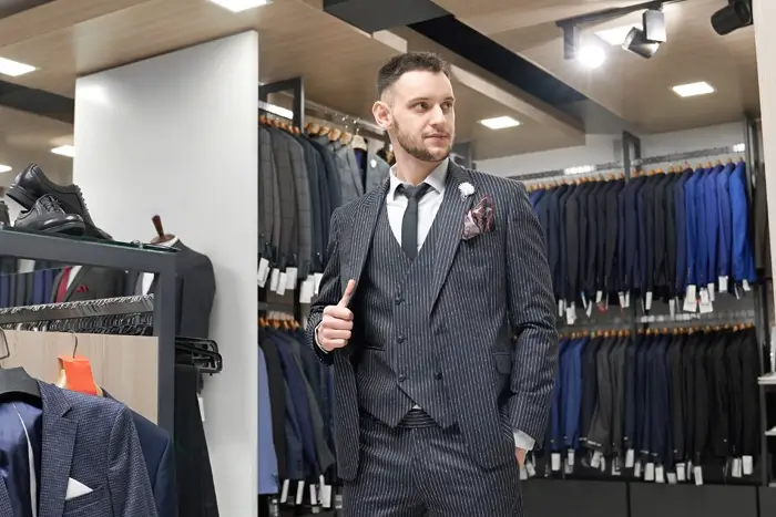 Gentleman posing in suit in showroom of boutique