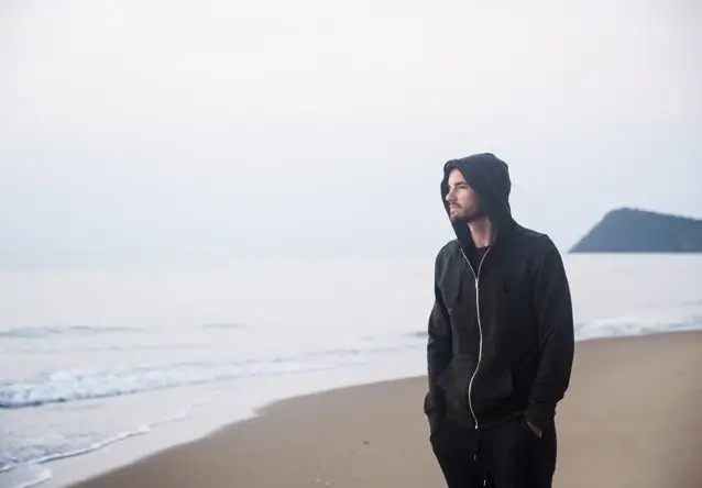 man wearing zip-up hoodies standing on beach