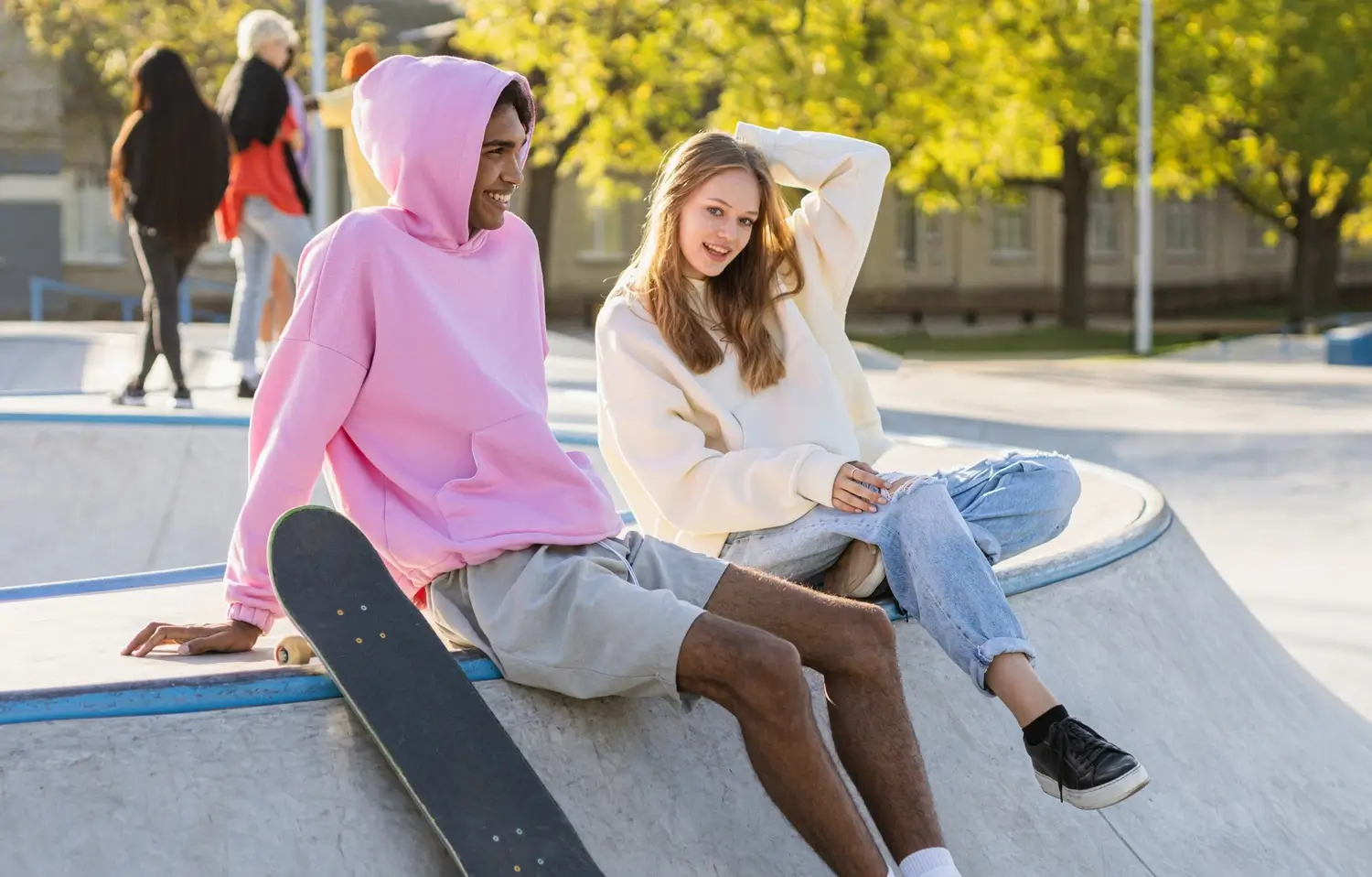 Stylish cool teens wearing hoodies gather at urban skate park