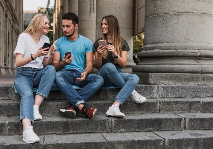 Young man in t-shirt sitting on stairs and looking at mobile phone
