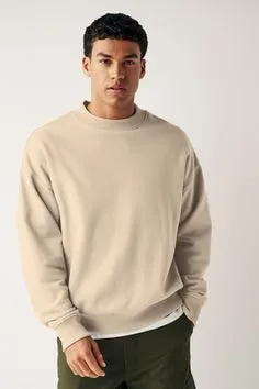 Person wearing a beige crew neck sweater with a classic round neckline, long sleeves, and ribbed cuffs, styled with dark pants for a casual look.