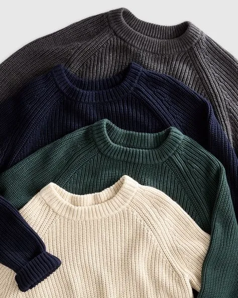 Stack of classic crew neck sweaters in cream, green, navy blue, and dark grey, showcasing versatile sweater styles for everyday fashion.
