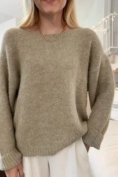 Person in a loose beige boat-neck sweater paired with white pants, showcasing relaxed types of sweaters for casual wear.
