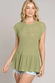 Person in a green sleeveless sweater with a peplum hem, paired with white shorts, showcasing unique types of sweaters for warm-weather styles.