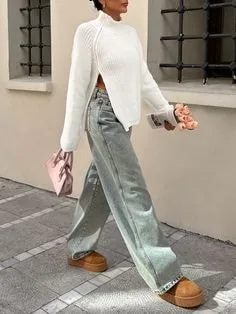 Person in a white high-neck sweater with side slits, paired with wide-leg jeans and brown boots, showcasing trendy types of sweaters for casual styles.