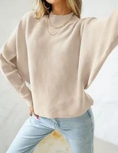 Person in a loose beige crew-neck sweater with voluminous sleeves, paired with light blue jeans, showcasing relaxed types of sweaters for casual styles.