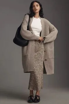 A long, oversized open-front cardigan styled with a white top and leopard print skirt, offering a relaxed yet chic ensemble.