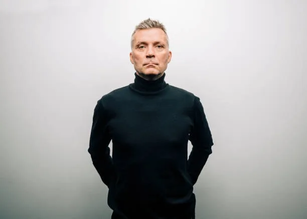 Person modeling a classic black turtleneck sweater against a minimalist background.