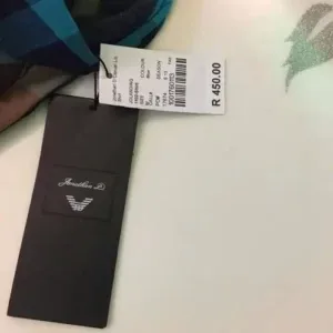 A black hang tag with barcode and price label attached to a designer garment, produced by a clothing manufacturer.