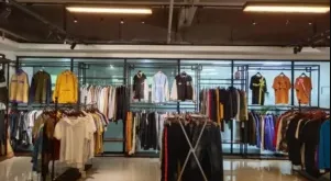 Modern showroom with racks of various apparel styles including jackets, hoodies, and shirts displayed by a clothing manufacturer.
