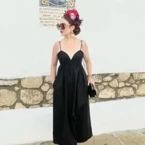 Woman in a black spaghetti strap midi dress, accessorized with floral headwear and sunglasses, created by a fashion clothing manufacturer.