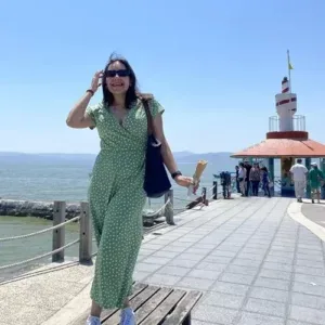 Woman in a green polka dot jumpsuit enjoying a day outdoors, wearing casual apparel from a lifestyle clothing manufacturer.