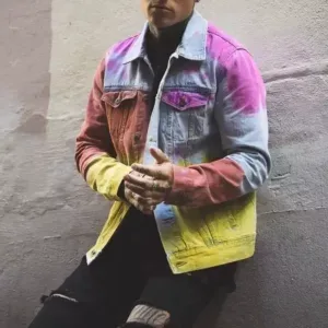 Man wearing a colorful denim jacket with gradient dye, posing against a wall, showcasing custom streetwear manufacturing.