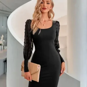 Woman in a form-fitting black dress with sheer sleeves, holding a beige clutch, styled by a dress manufacturer.